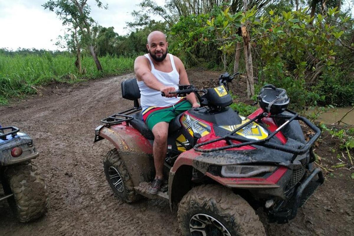 un home assegut en un quad en un camí de terra