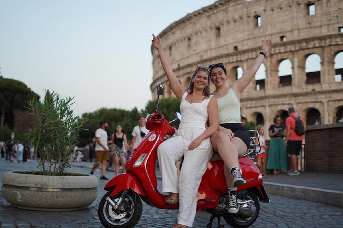 due donne sedute su uno scooter rosso davanti al Colosseo