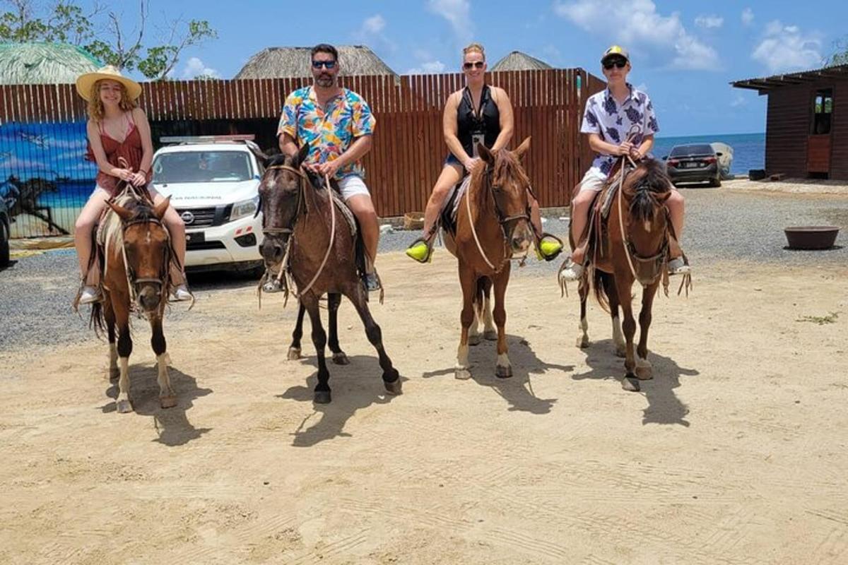 a group of people sitting on horses in the dirt