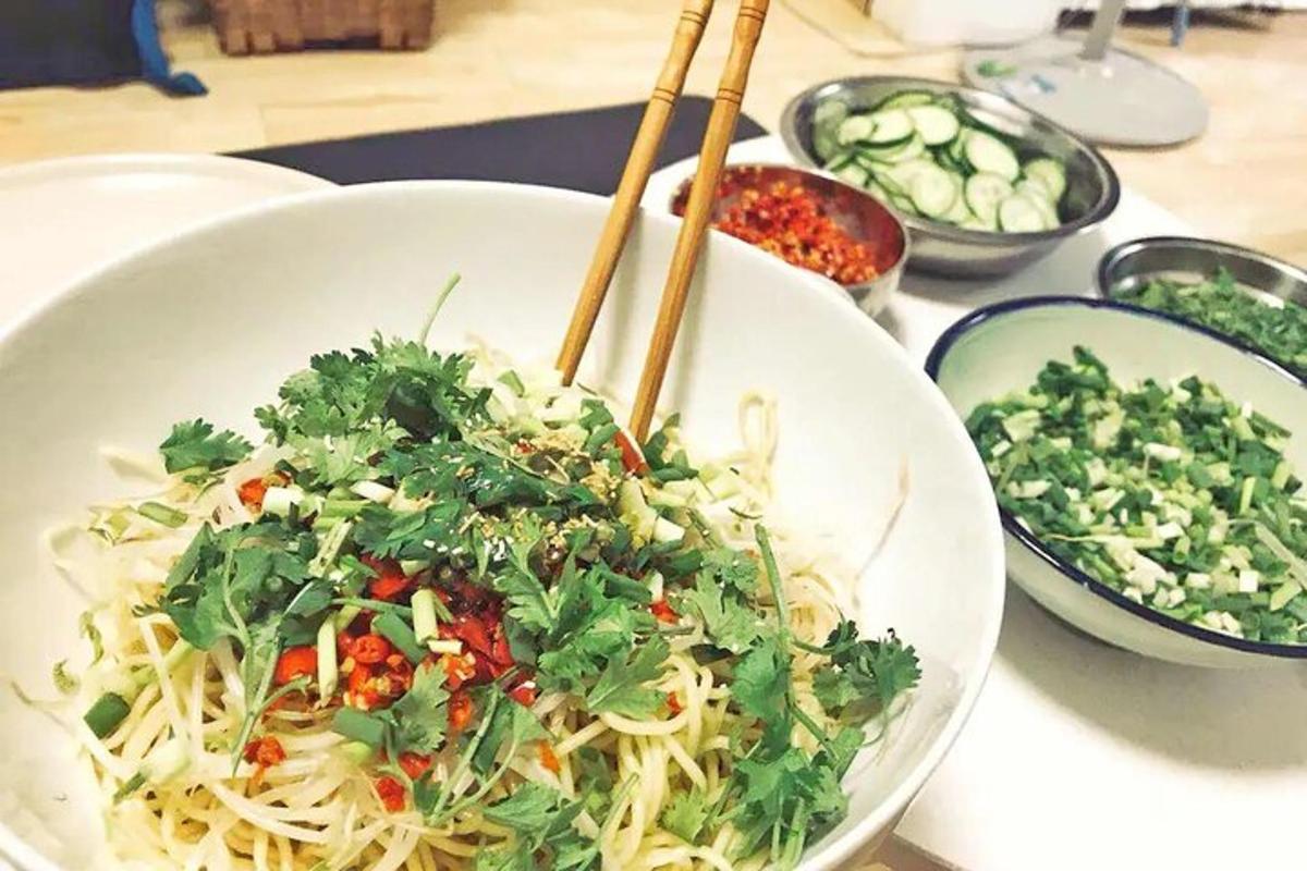 a bowl of noodles and vegetables on a table with chopsticks