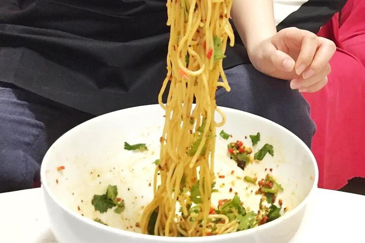 a person is holding a bowl of noodles