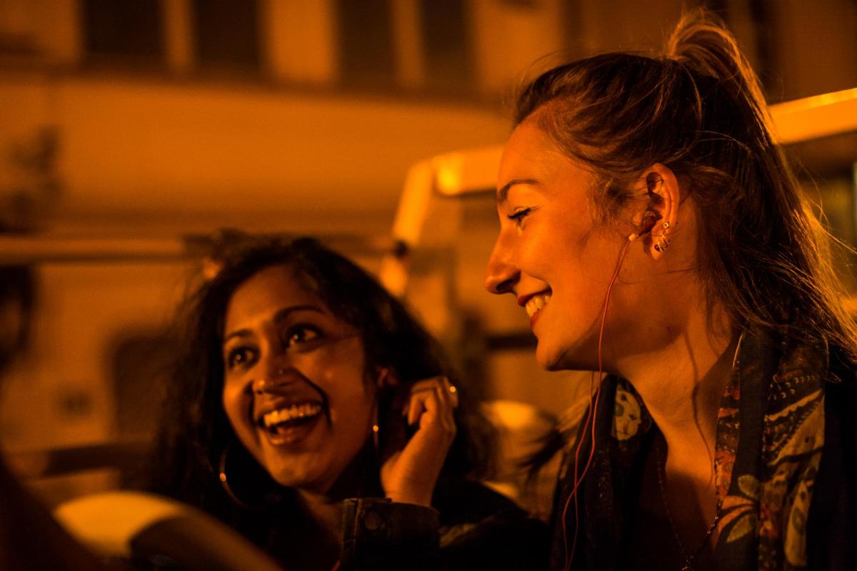 two women laughing while talking on a cell phone