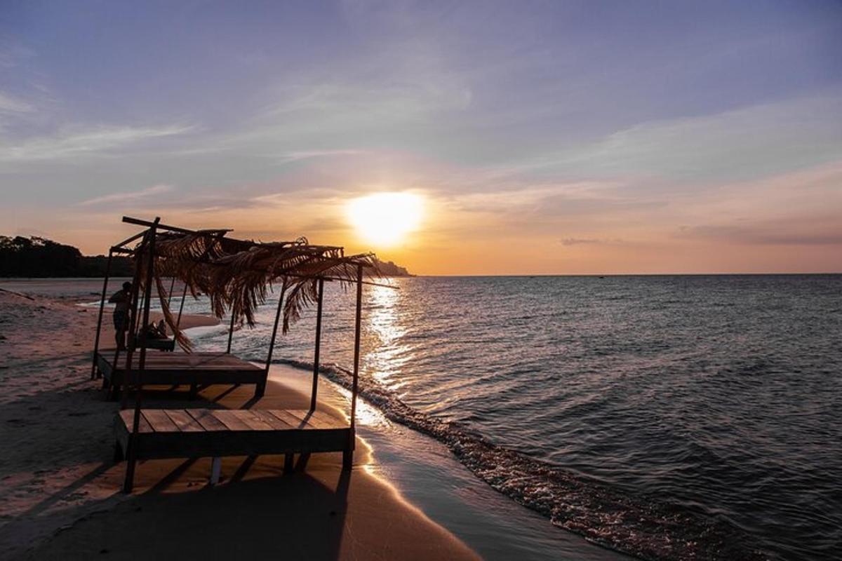 a bed on the beach with the sunset in the background