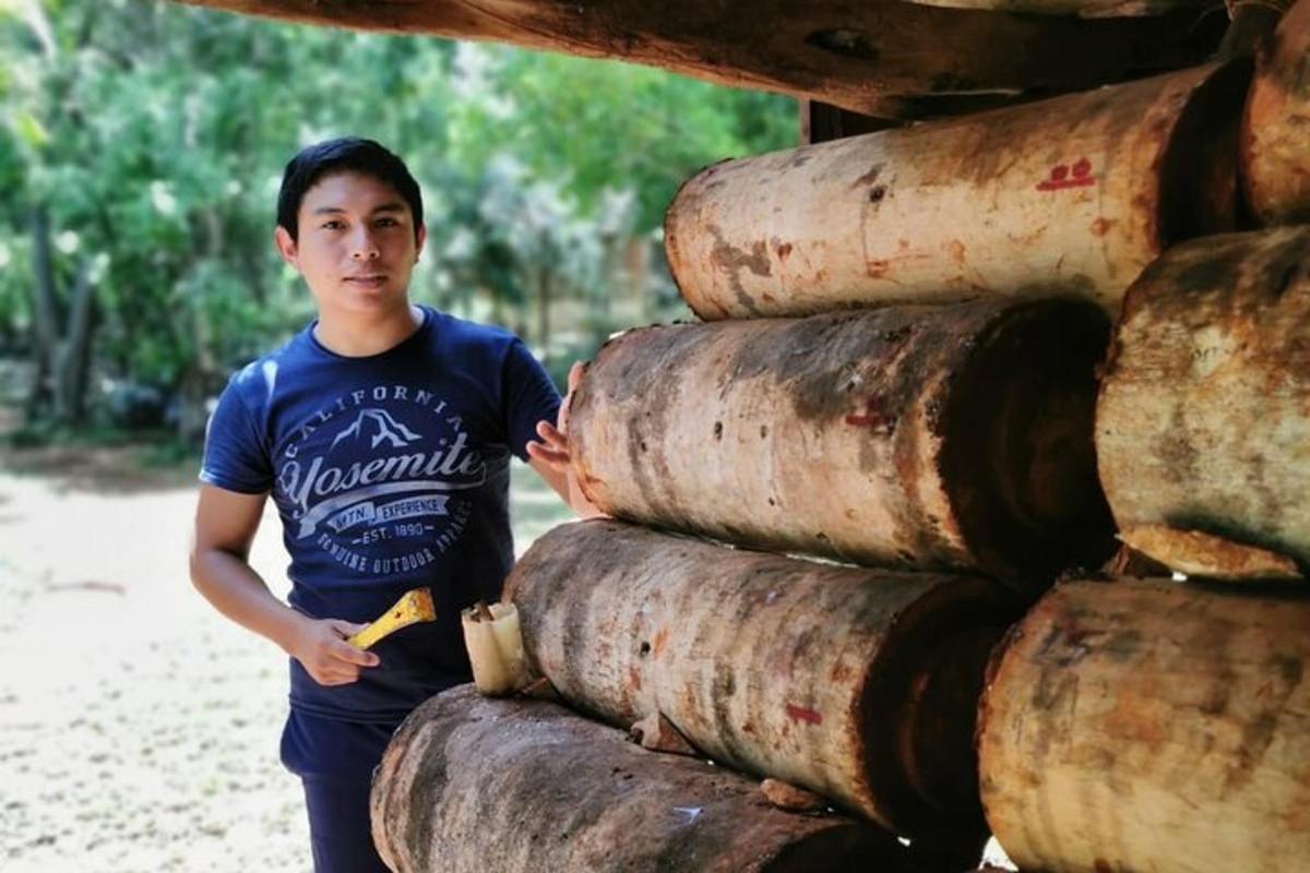 un uomo in piedi accanto a una pila di botti di legno