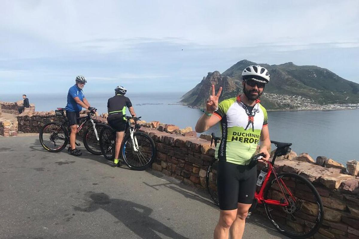 Un grupo de personas de pie junto a una pared con sus bicicletas.
