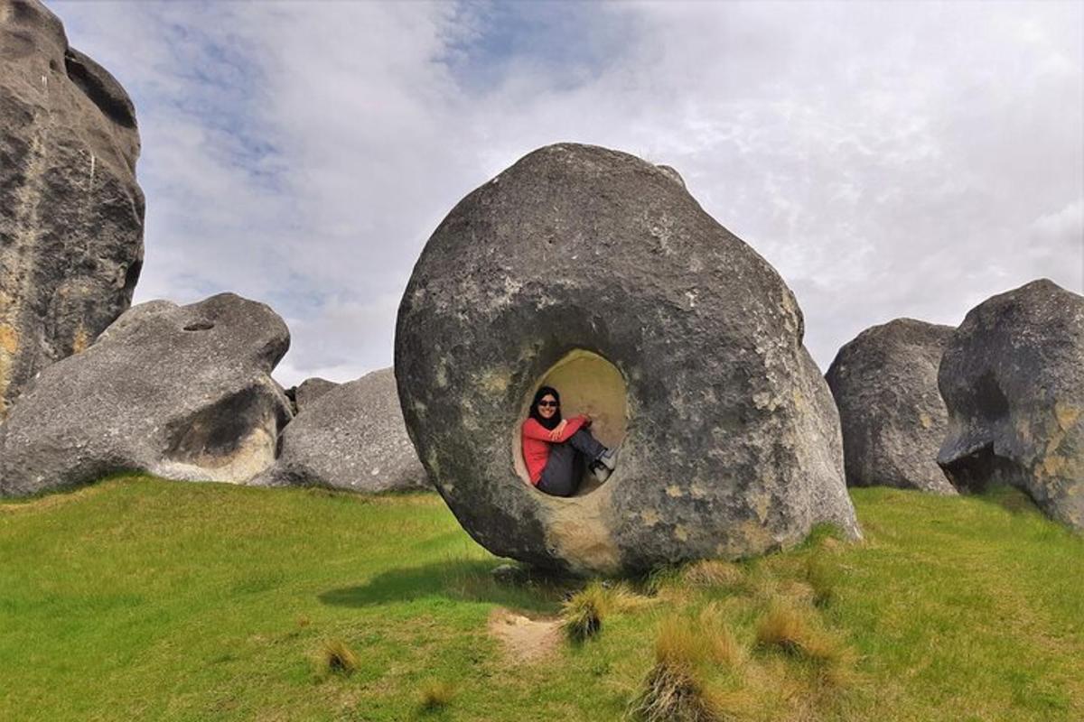 a woman is sitting inside of a large rock
