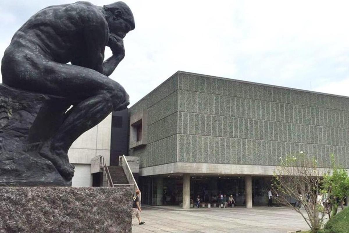 a statue of a thinker in front of a building