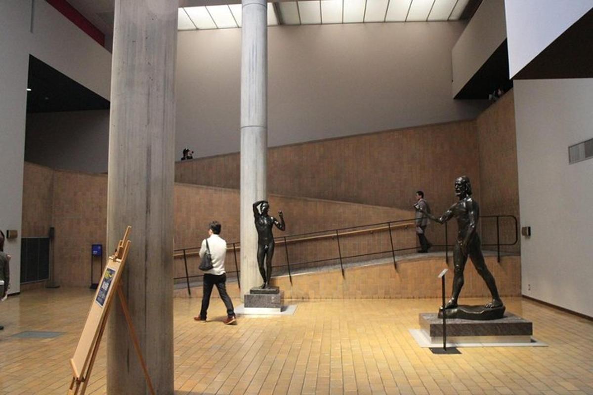 a man walking past statues in a room with a column