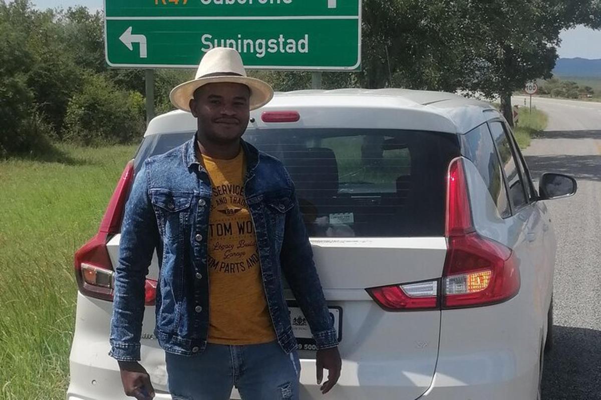 um homem usando um chapéu parado ao lado de um carro branco