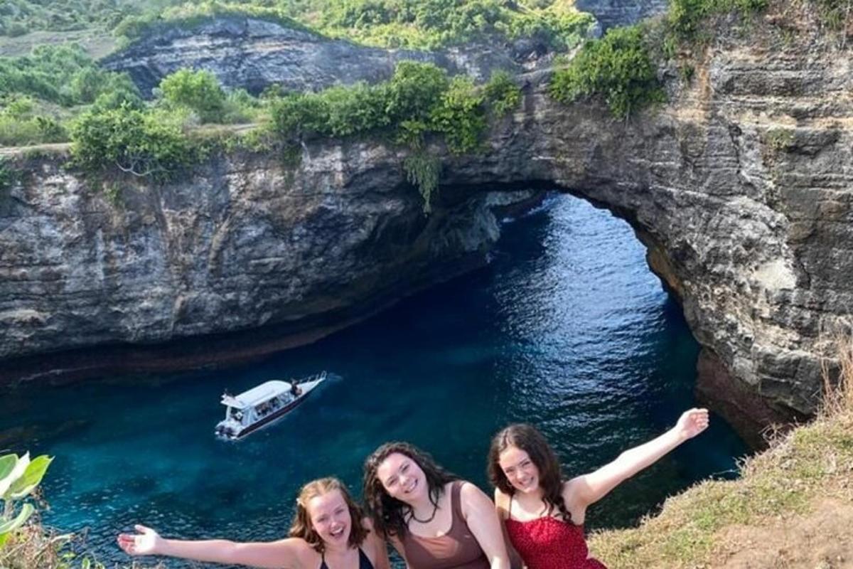 tre ragazze posano davanti a una grotta con una barca