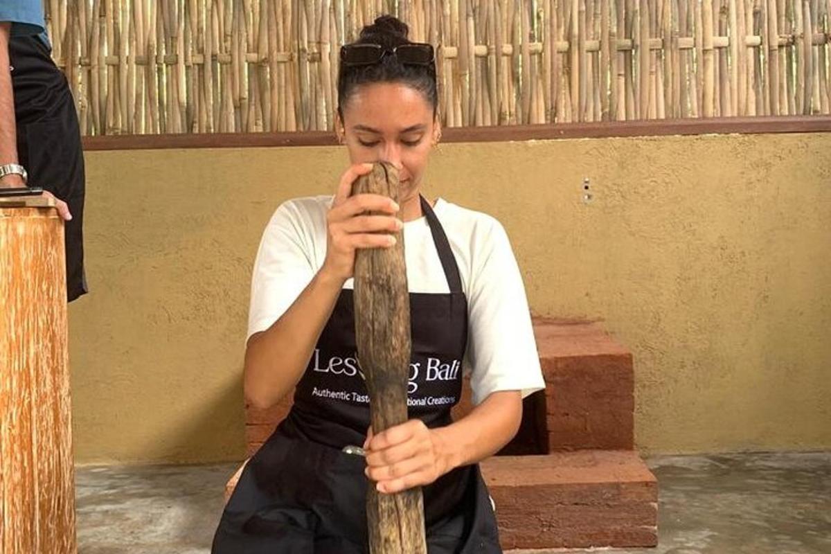 Una mujer con un delantal sosteniendo un instrumento de madera.