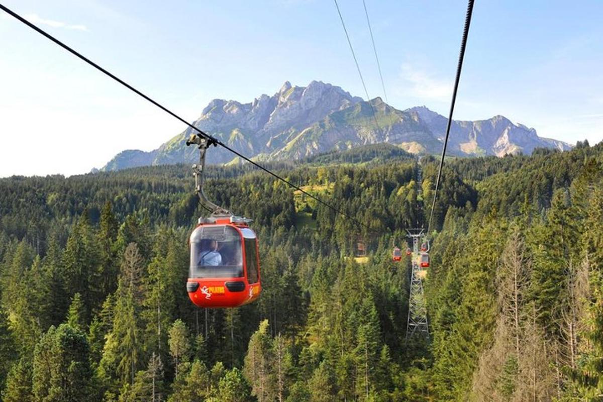 červená lanovka letící nad horou