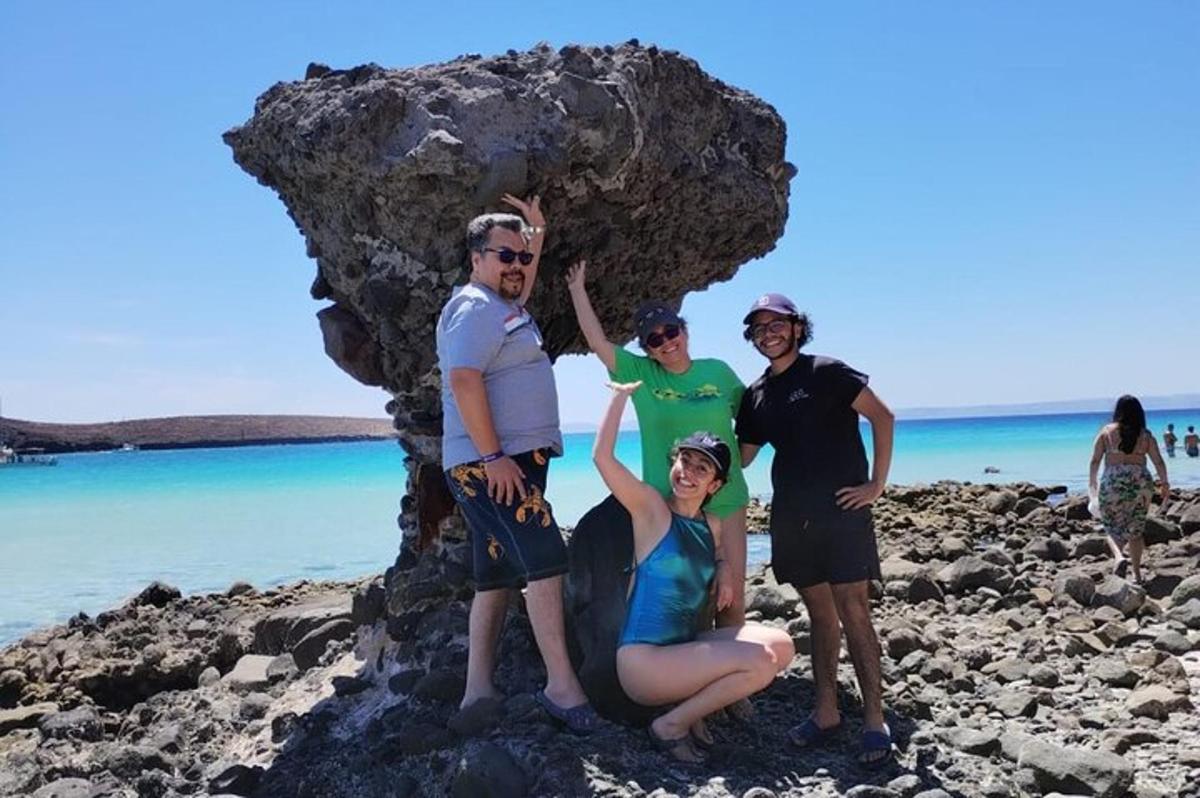 um grupo de pessoas em pé ao lado de uma rocha na praia