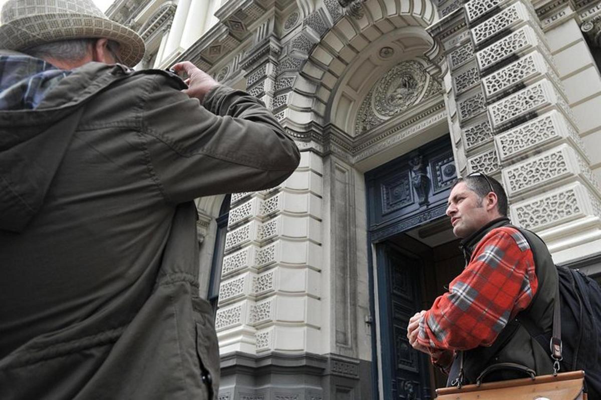 a man taking a picture of a man standing outside of a building