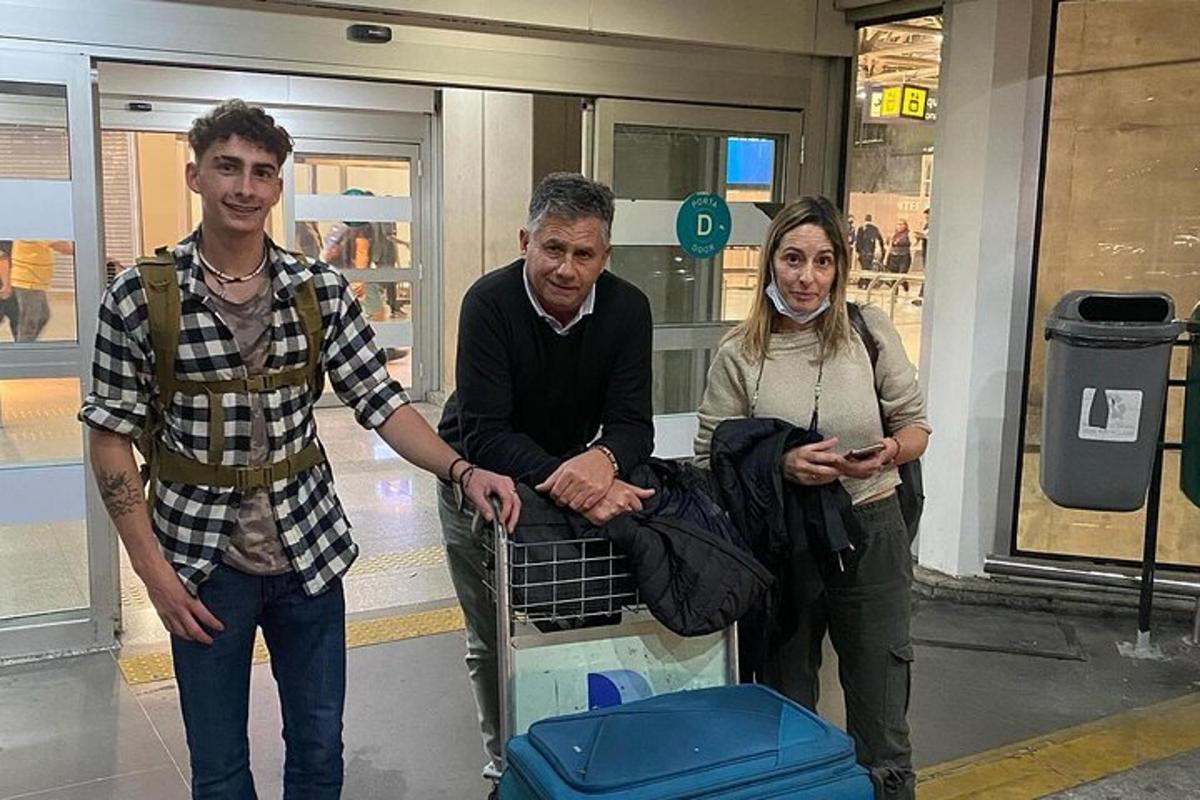 dva muži a žena stojící před vozíkem na zavazadla