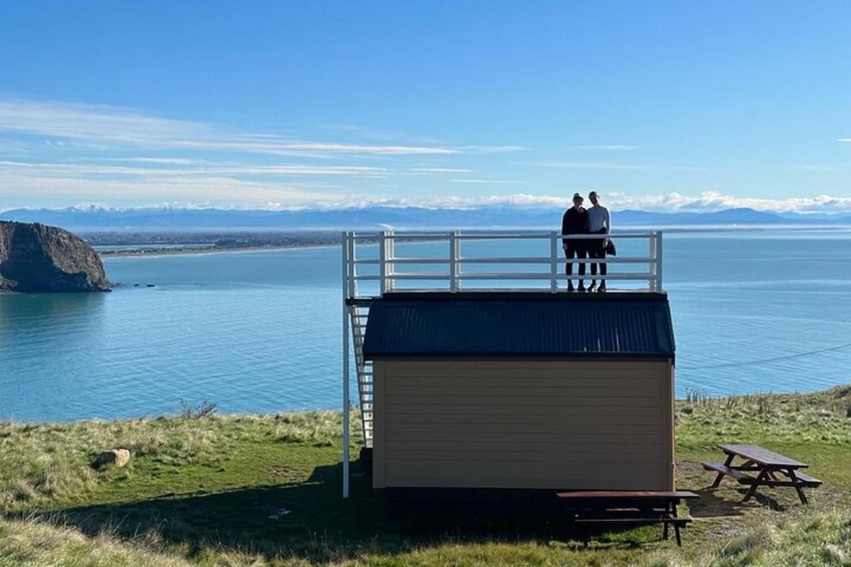 two people standing on top of a tower overlooking a body of water
