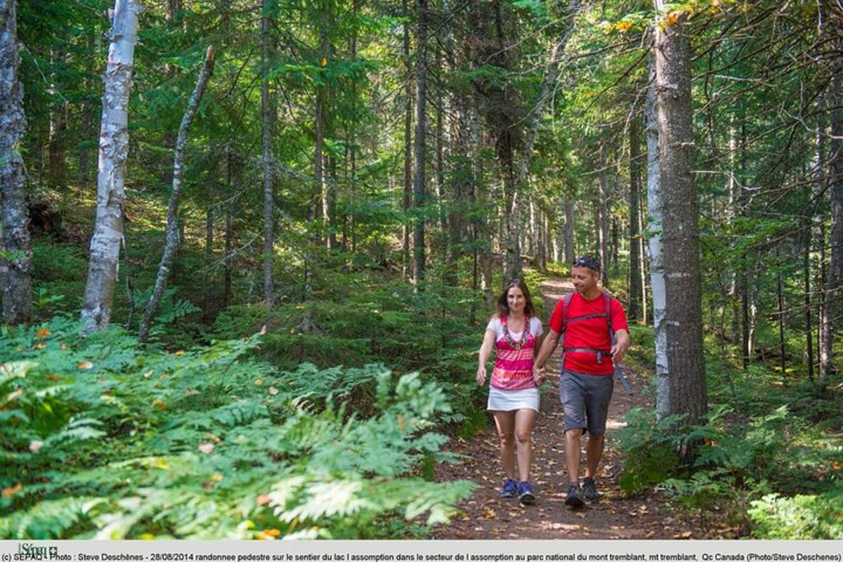 a man and woman walking down a trail in the woods