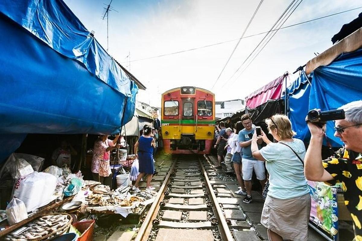 sekumpulan orang mengambil gambar kereta api di sebuah pasar