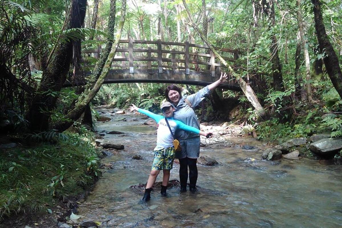 a man and a child standing in a stream with a bridge