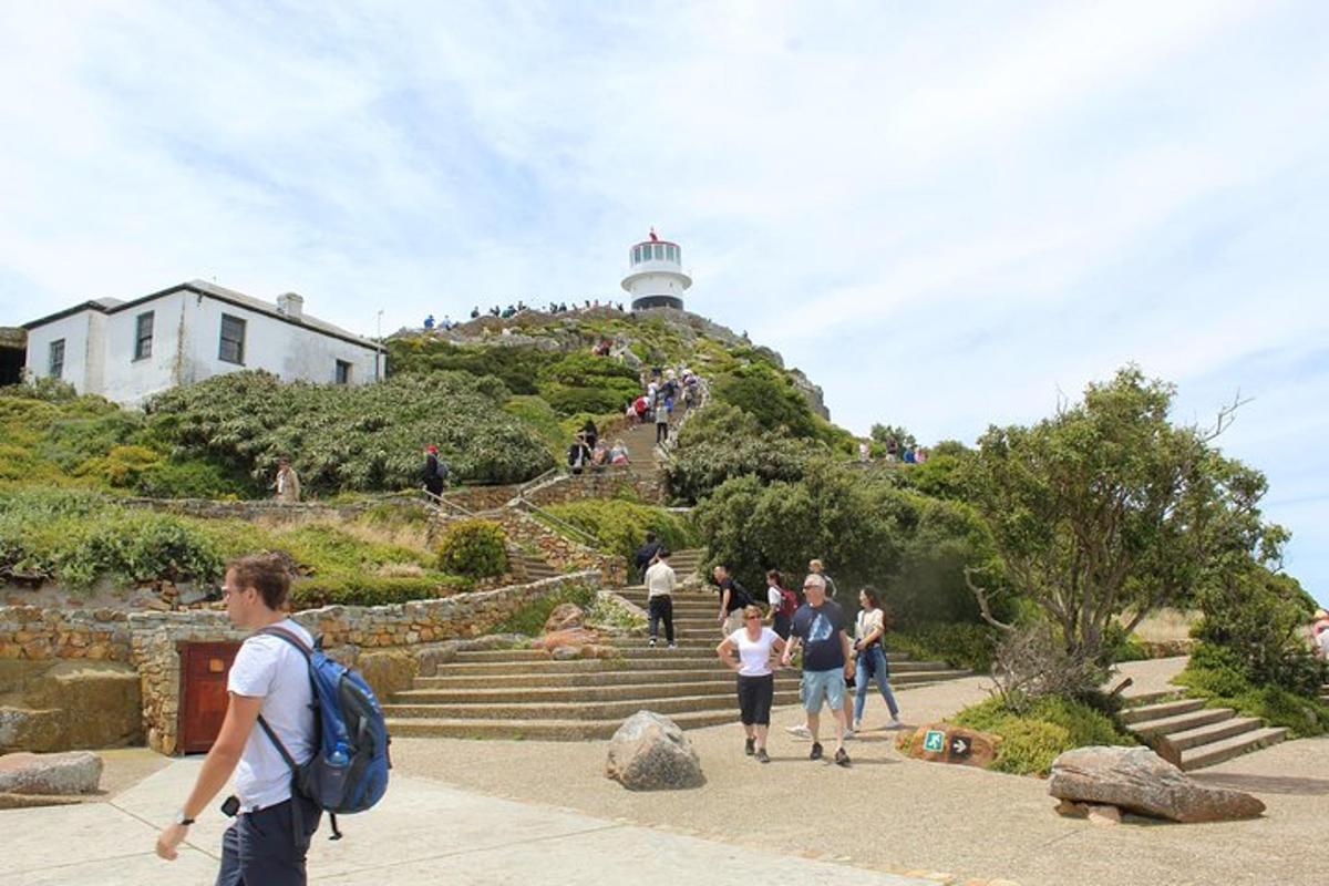 a group of people walking up the stairs to a lighthouse