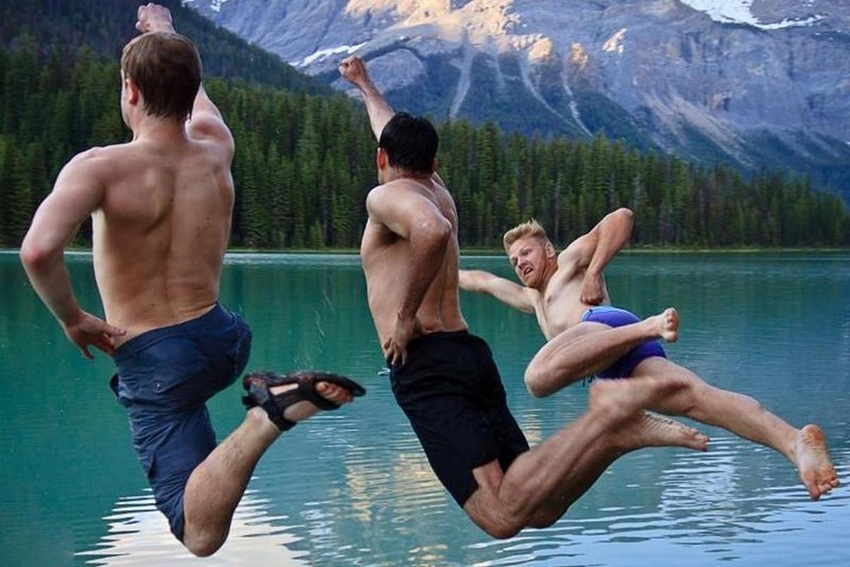 três homens pulando na água de um lago