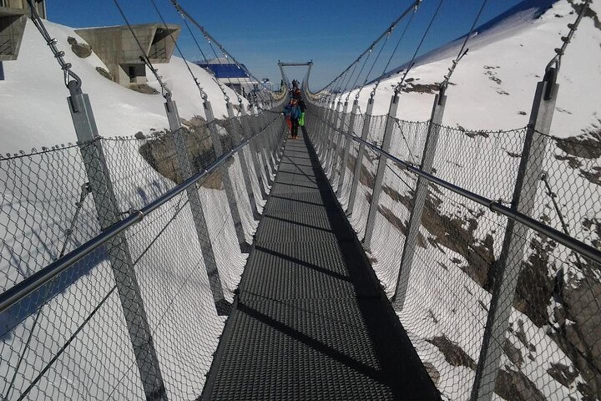 una persona che cammina su un ponte sospeso sopra una montagna innevata