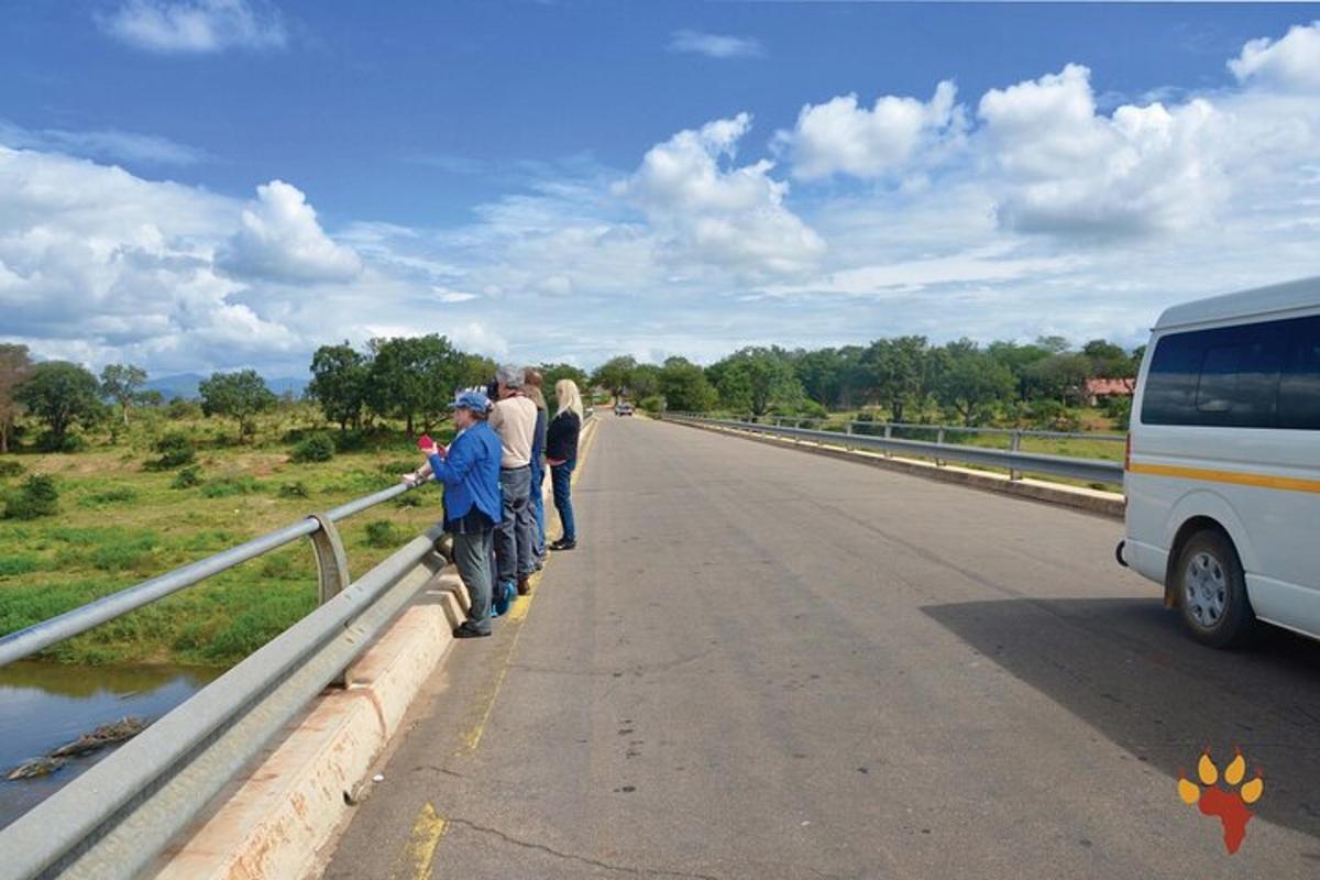 sekelompok orang berdiri di jembatan di samping bus