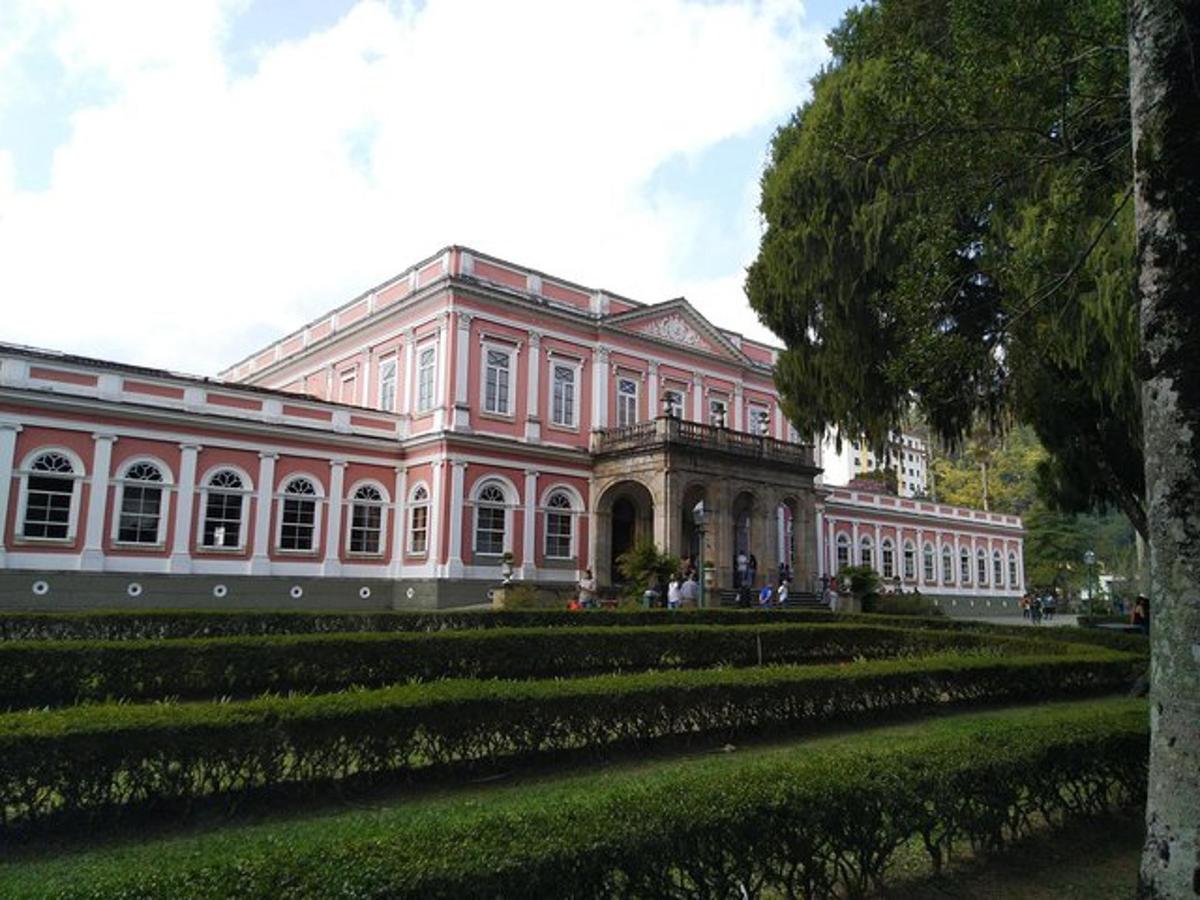 un grande edificio rosa con un giardino di fronte