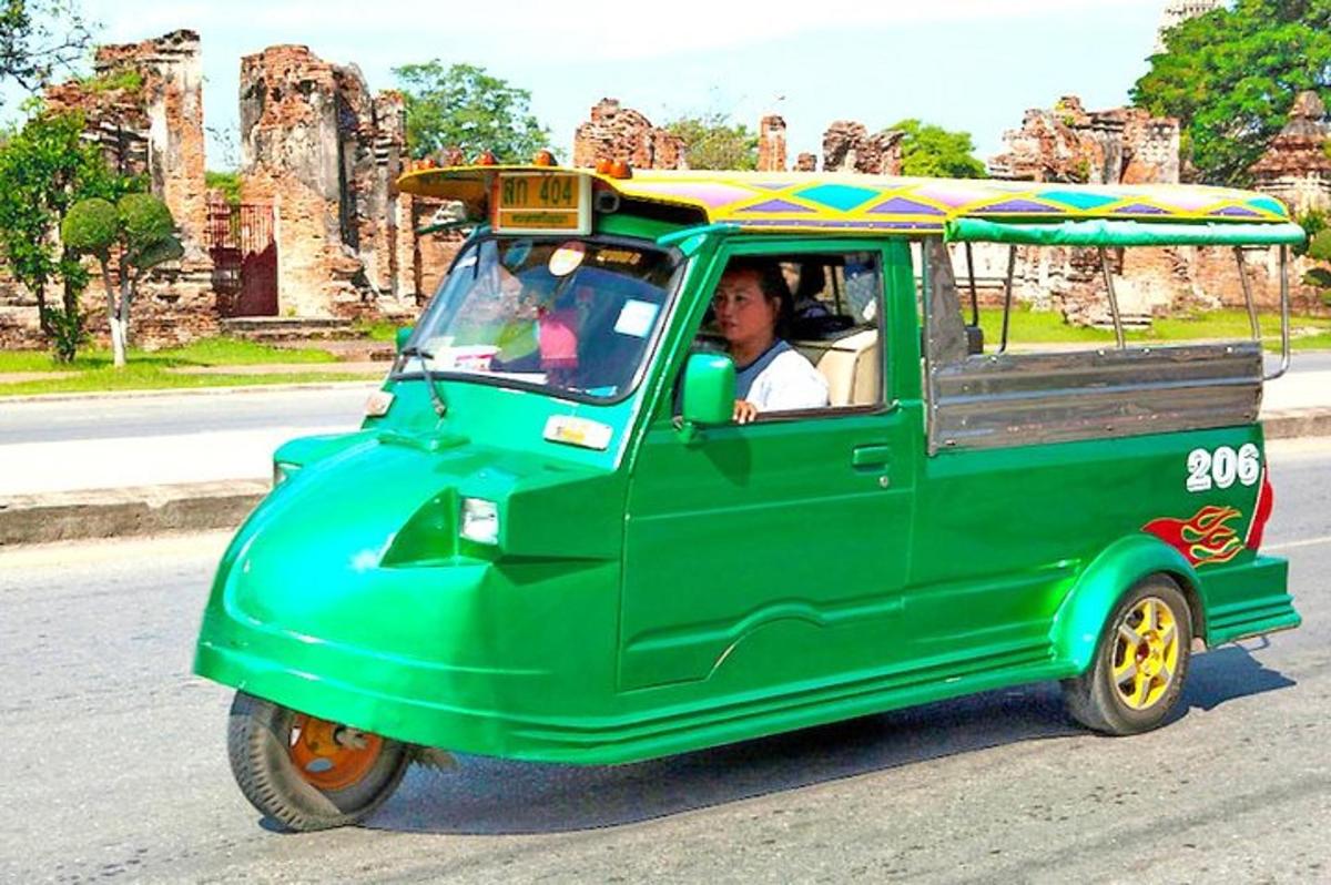 một người lái một chiếc xe nhỏ màu xanh lá cây với một chiếc ô