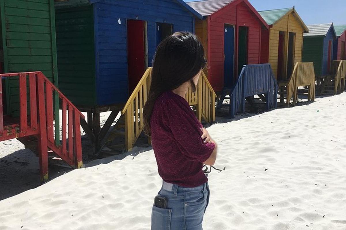 a woman standing in front of a row of colorful beach houses
