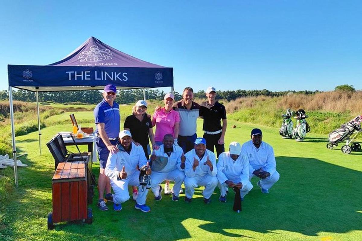 grupp inimesi poseerib golfiväljakul pildi jaoks