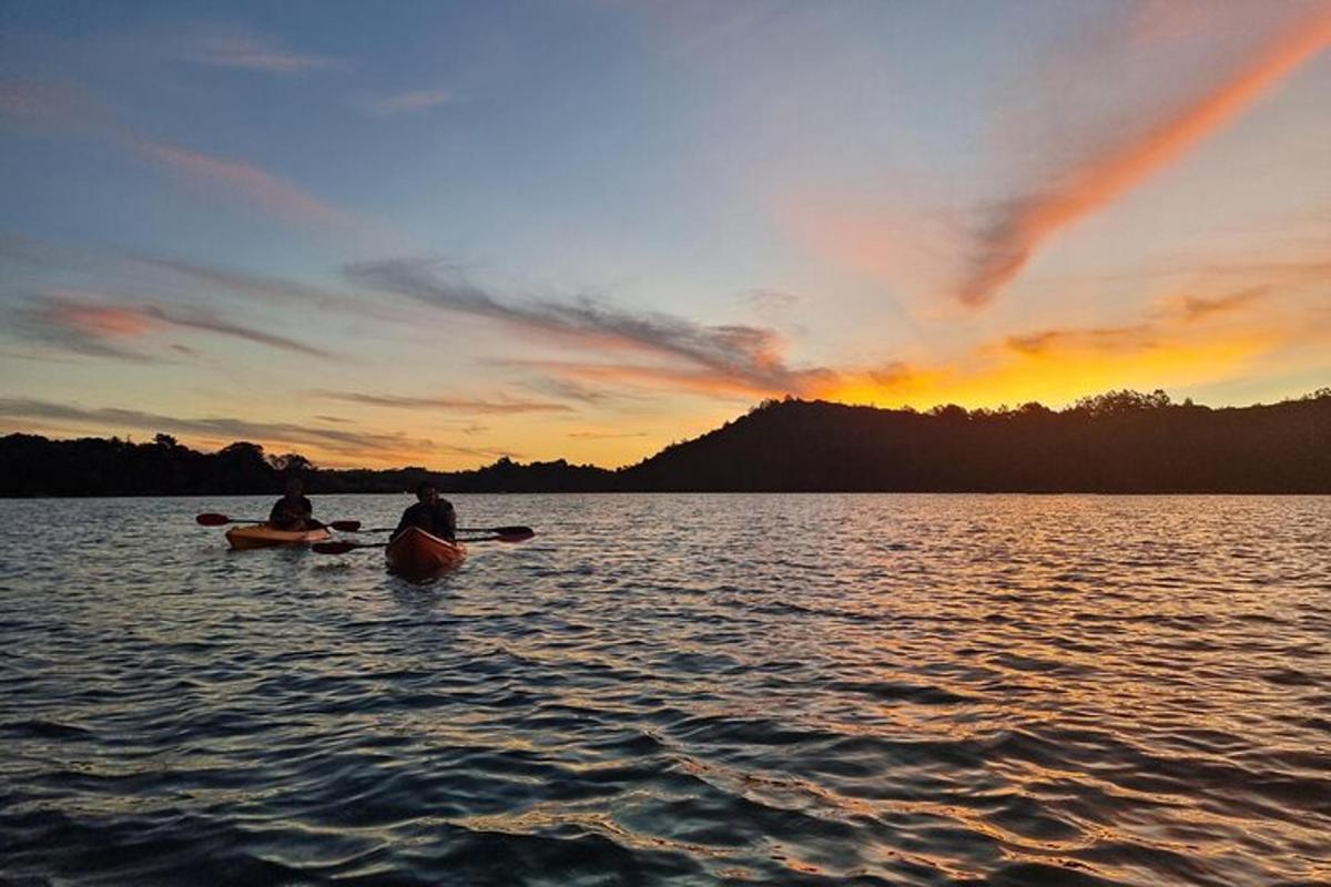 two people in kayaks on a lake at sunset