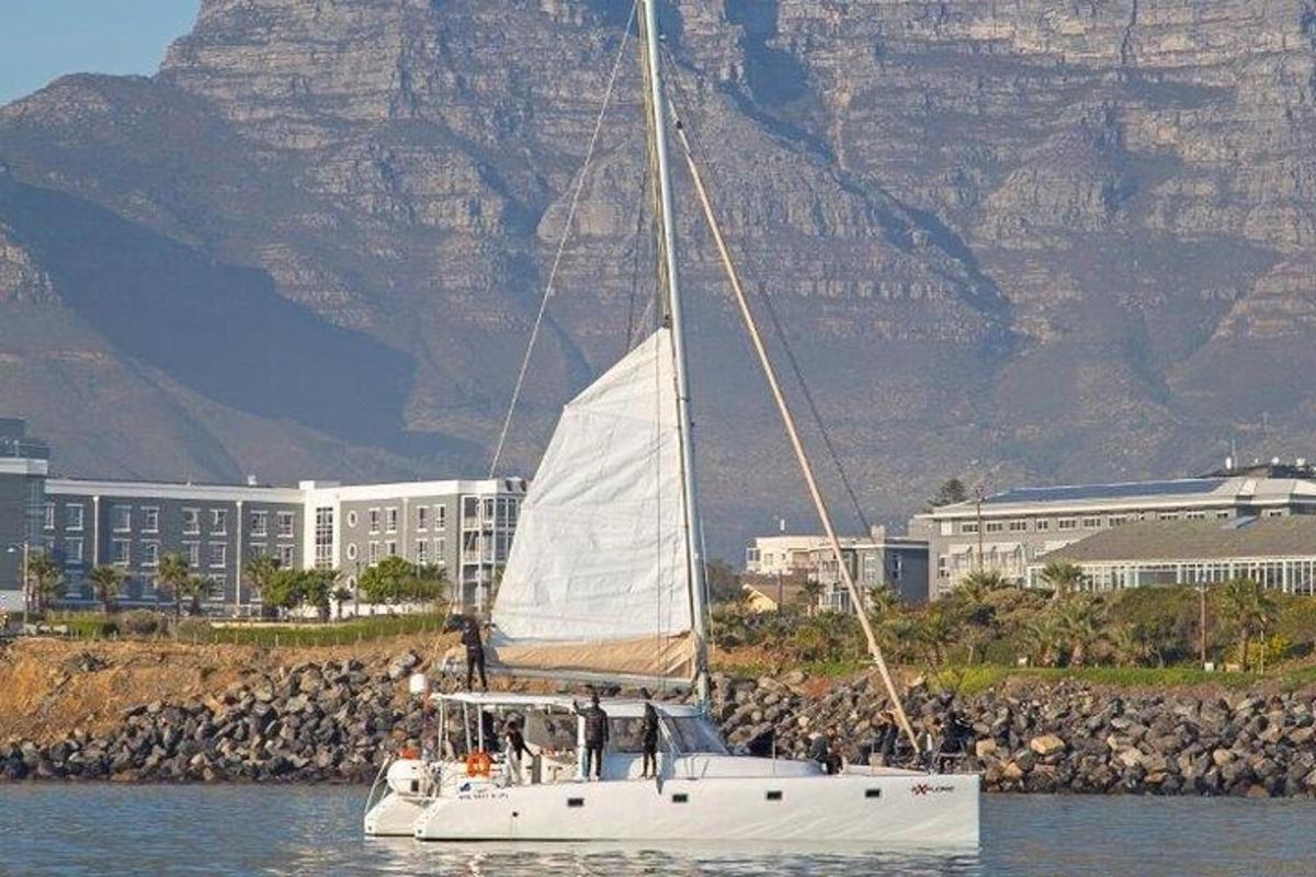 ein weißes Segelboot mit Menschen darauf im Wasser