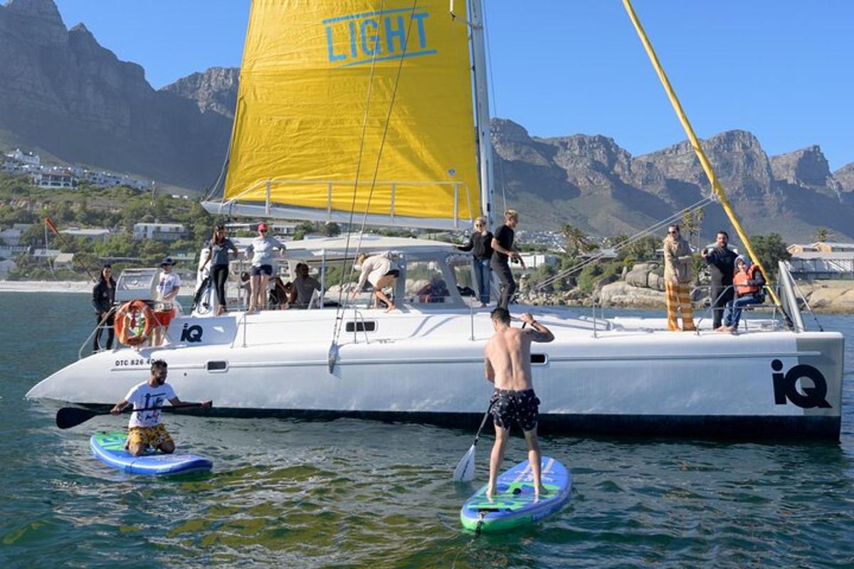 eine Gruppe von Menschen steht auf Surfbrettern vor einem Segelboot