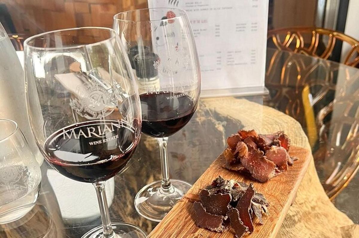 duas taças de vinho tinto e uma tábua de corte com carne