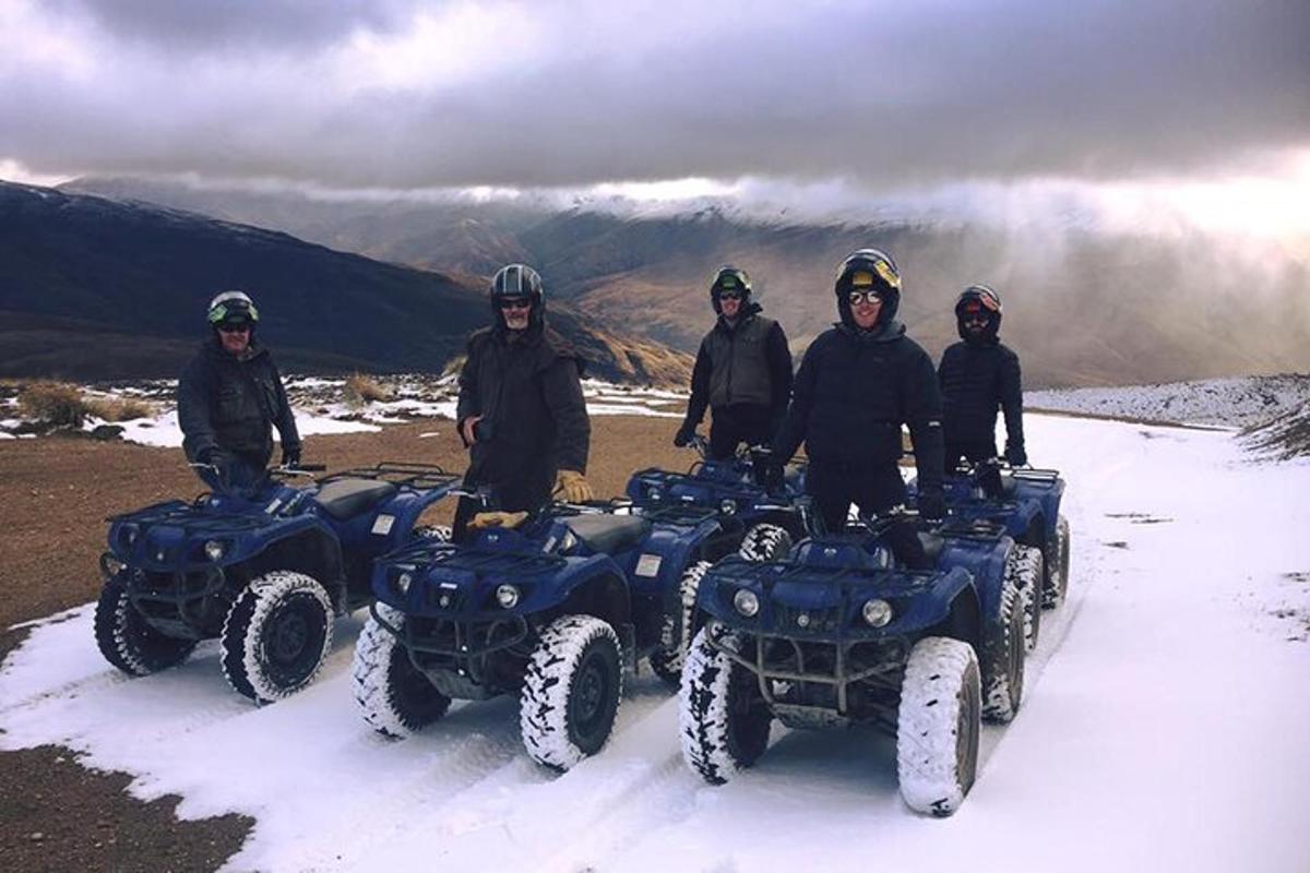 Un grupo de personas de pie en vehículos todo terreno en la nieve.