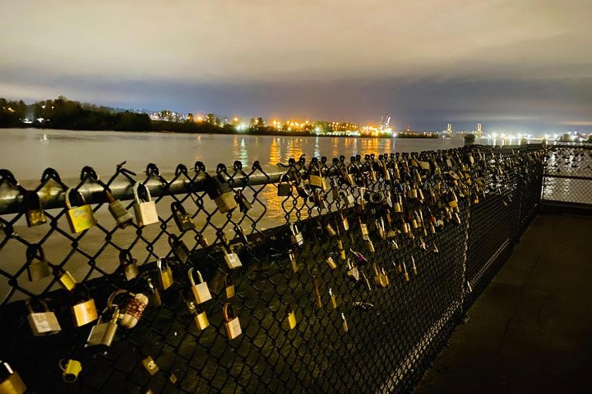 a bunch of wine bottles on a fence next to the water