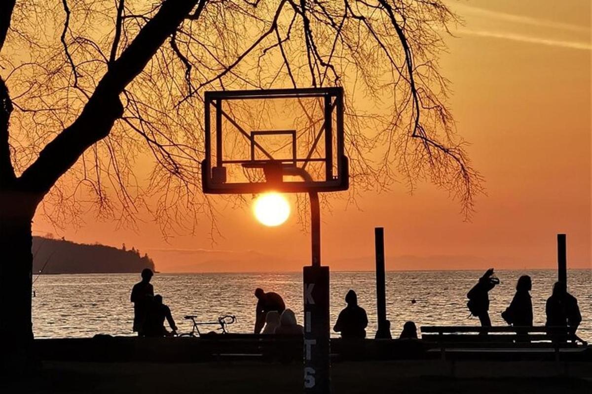 a group of people standing around a basketball hoop at sunset