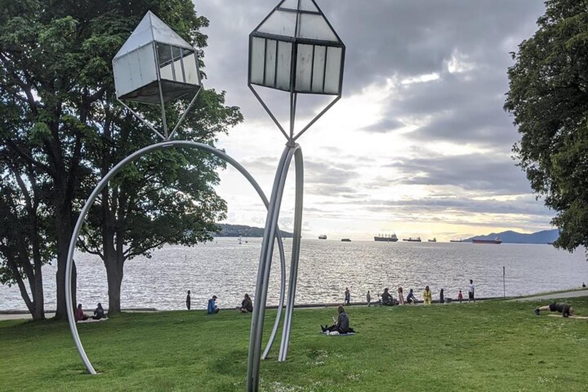 a sculpture of two lights in the grass near a body of water