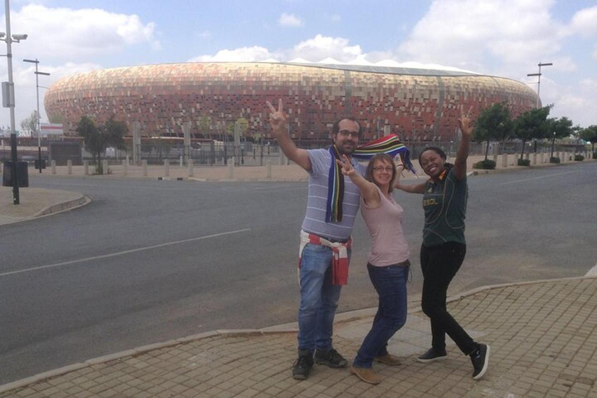 skupina tří lidí stojící před stadionem