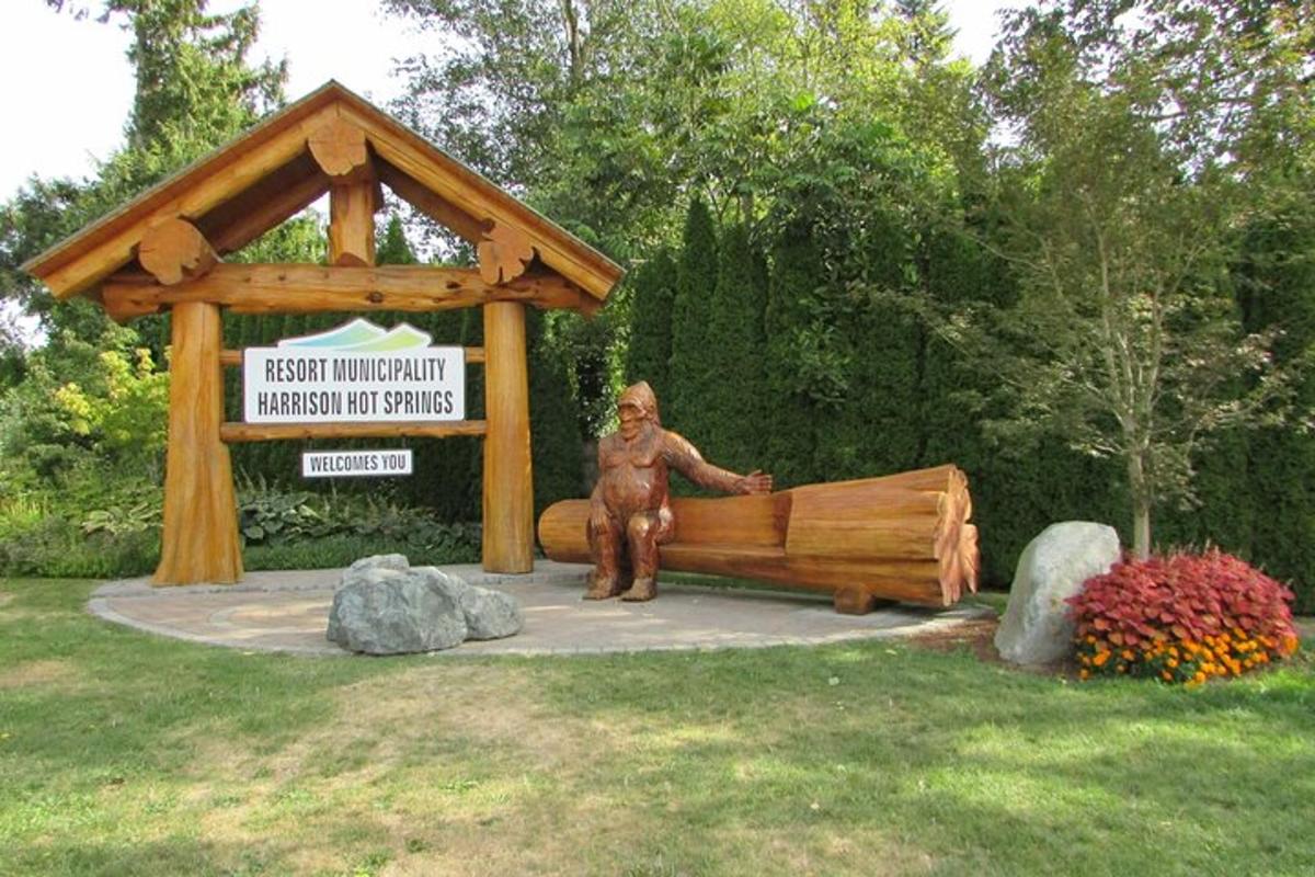 una statua di un uomo seduto su un letto di legno in un parco