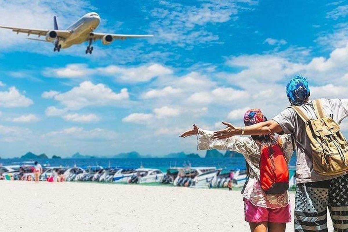Două persoane care stau pe o plajă și privesc un avion