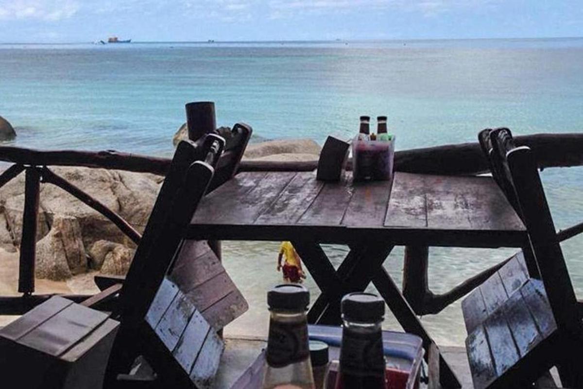 une table de pique-nique sur la plage avec des bouteilles de bière dessus