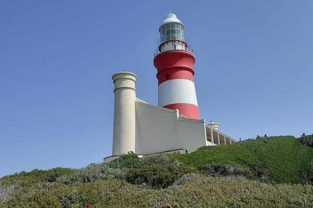 un faro rosso e bianco in cima a una collina