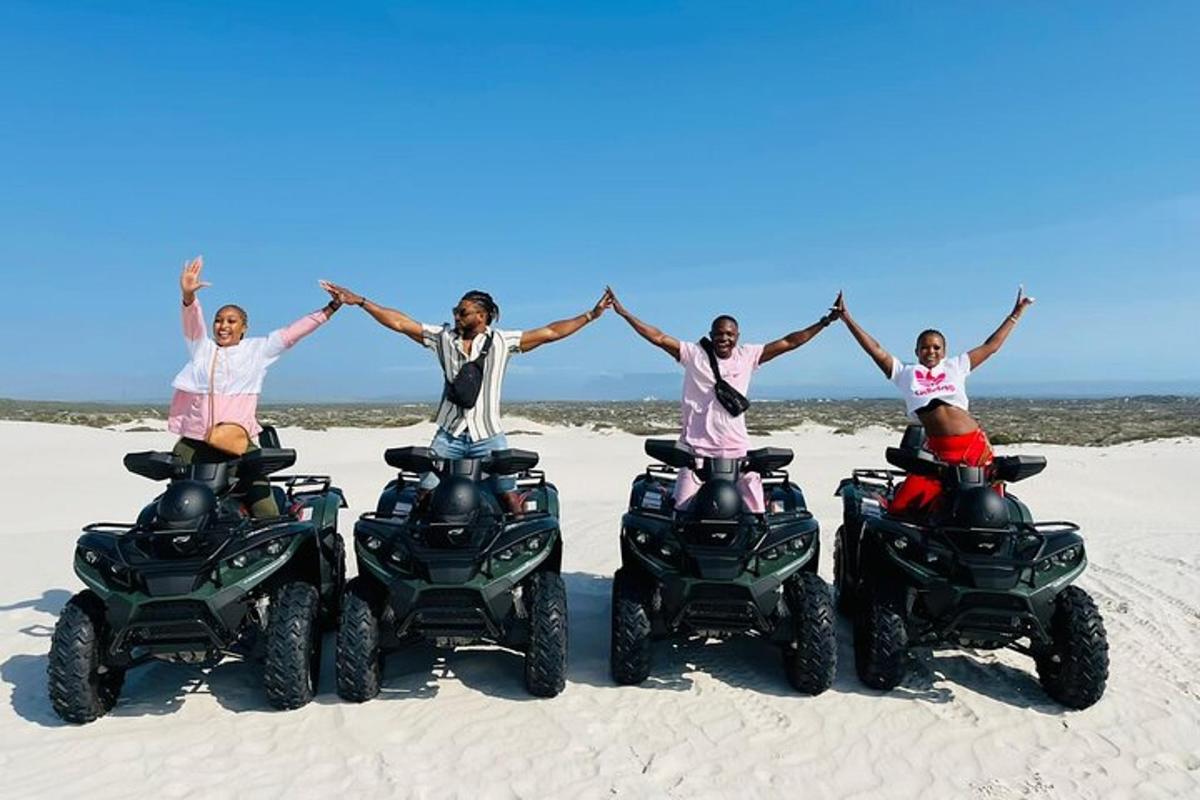 empat orang mengangkat tangan sambil menunggang atv di pantai