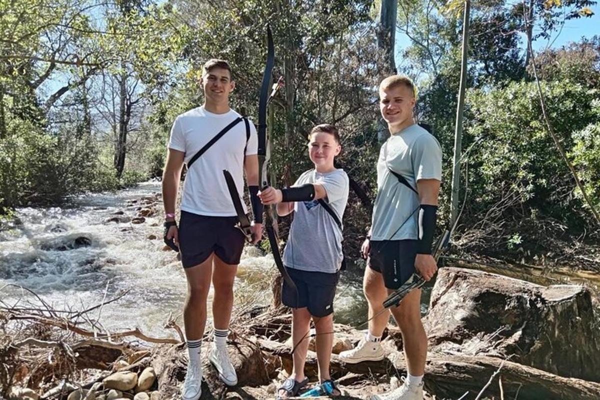 a group of three people standing next to a river