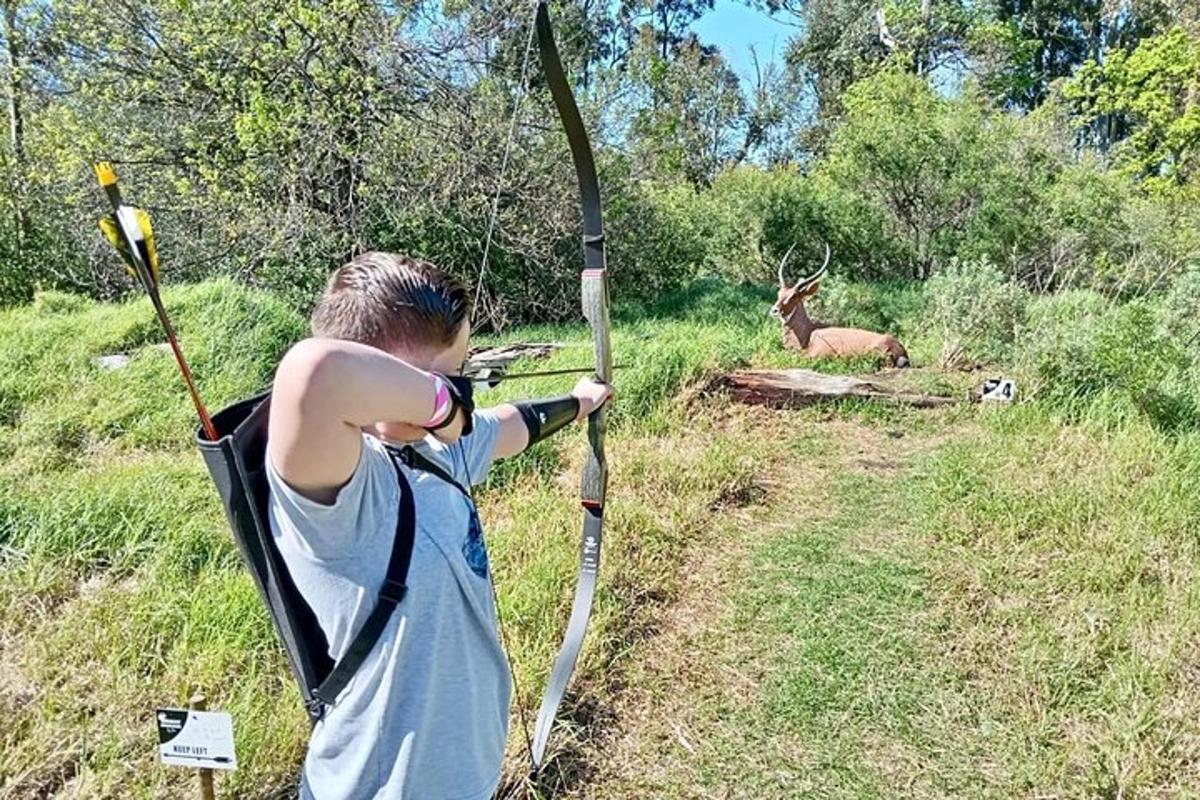 a young boy holding a bow and arrow in front of a deer