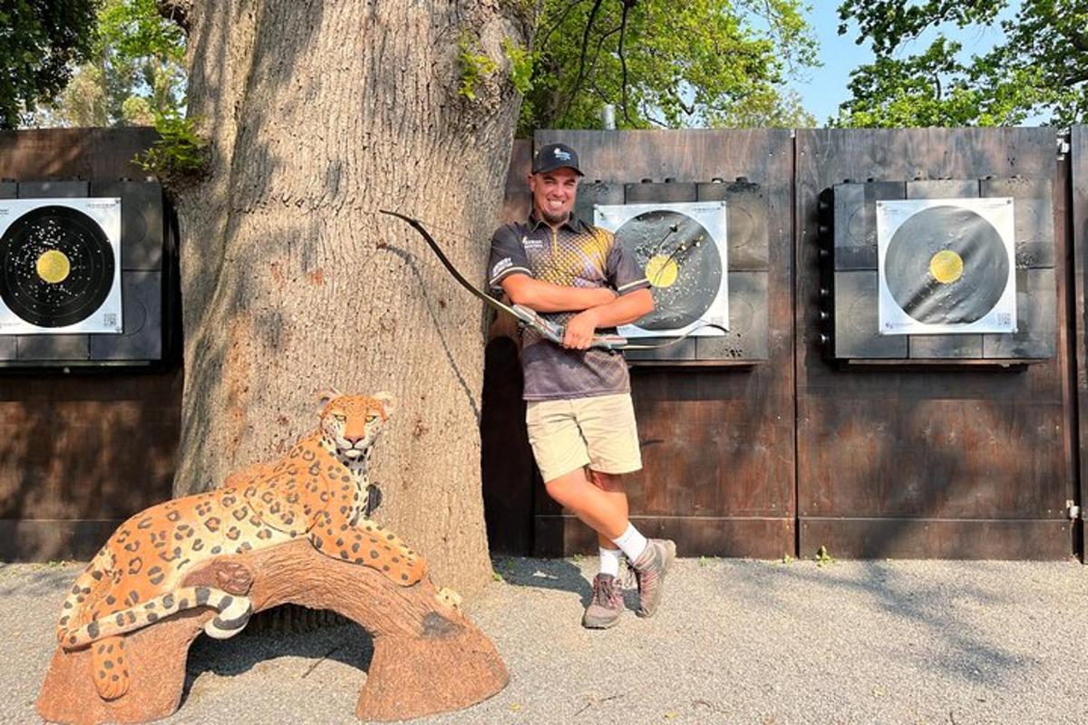 a man standing next to a tree with a bow and a leopard