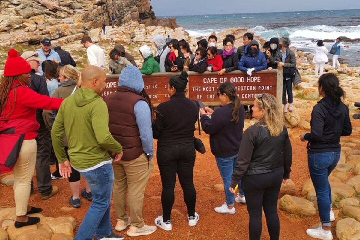 um grupo de pessoas em pé ao redor de uma placa na praia