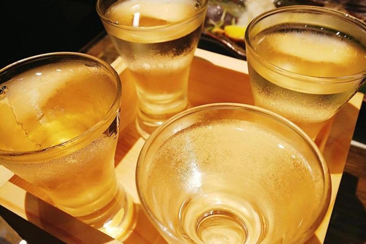 four glasses of beer sitting on a wooden table